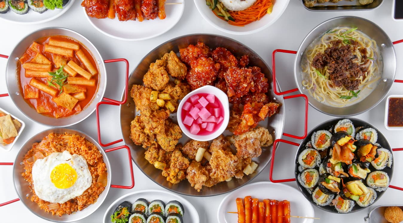 An overhead spread of GoGoDak Korean fried chicken, kimbap, tteokbokki, and other menu favorites